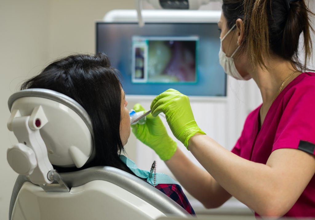 Odontóloga realizando procedimiento dental a paciente.