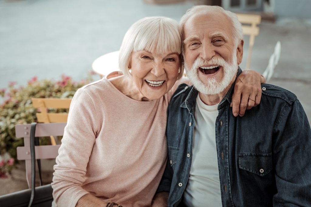 Pareja de adultos mayores sonriendo alegremente mientras se abrazan