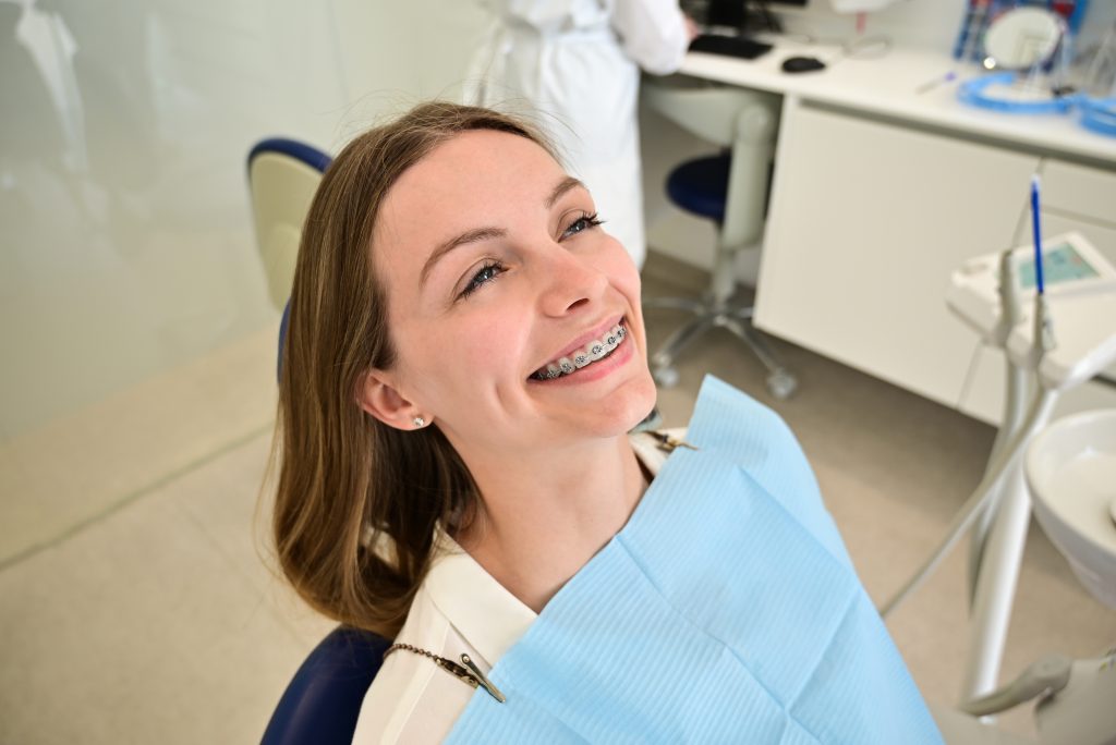 Paciente sonriente con brackets en consulta dental.