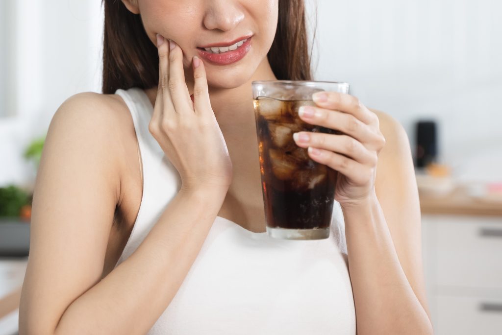 Mujer con sensibilidad dental al beber frío.